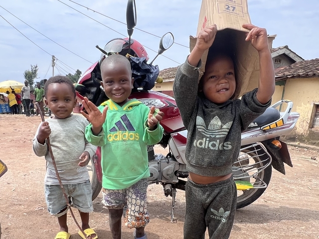 Three young children having fun in front of a motorbike.