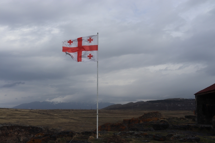 Georgian flag waving with mountains in the background.