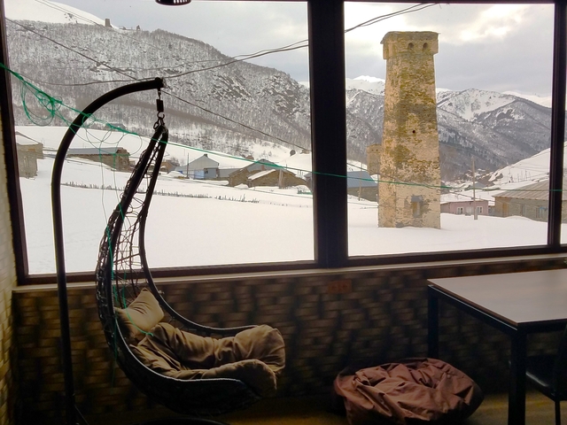 Snowy village with mountain views seen from a window.
