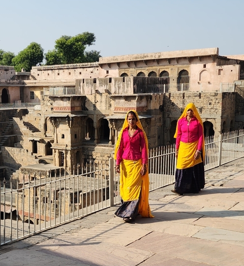 Two women in traditional attire walking on a historical site.
