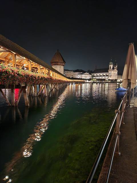 Wooden bridge lit up at night over water.