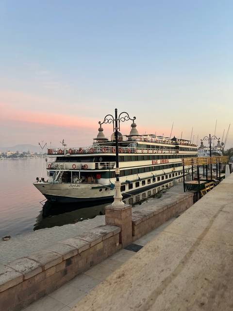Cruise ship docked at a port with a setting sun.
