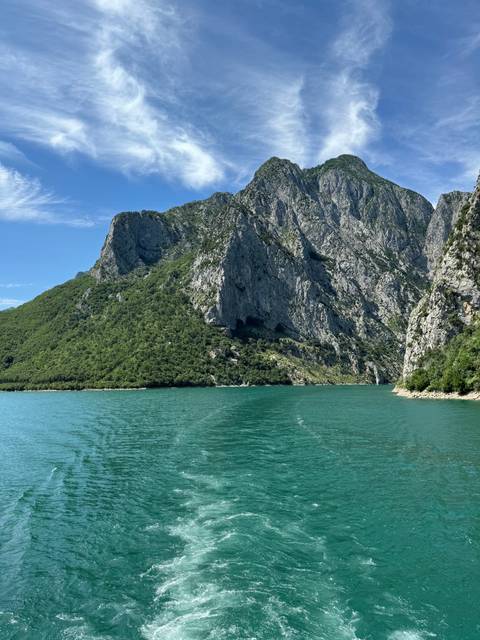 Steep rocky mountains next to a vibrant blue river.