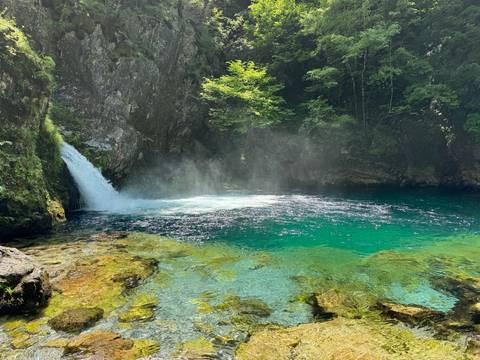 A waterfall in a lush, green, rocky landscape.