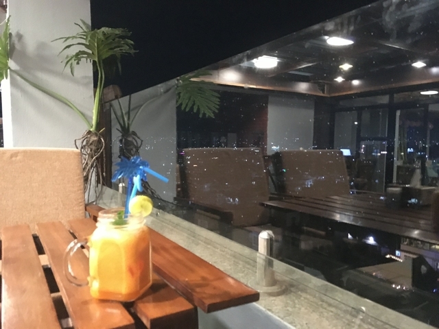 Glass of orange juice on a rooftop at night with a city view.