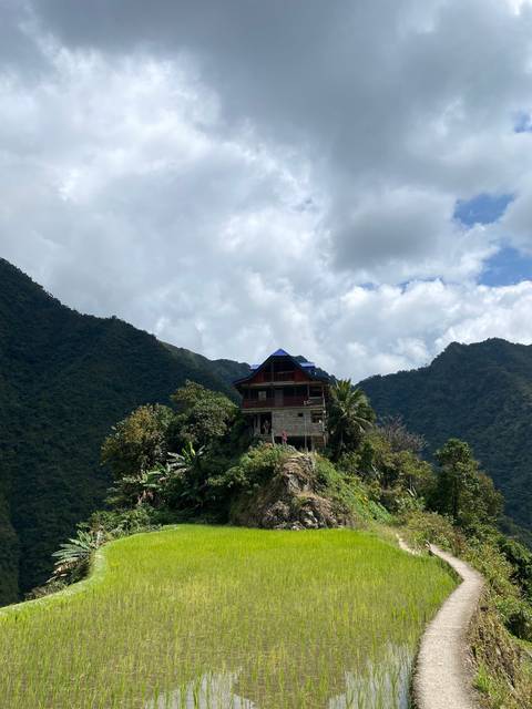 House with rice terraces and mountains in the background.