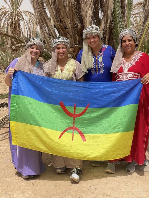Group in traditional dress holding a colorful flag.