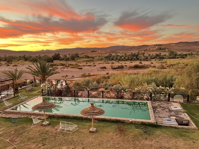 Resort with pool and a scenic desert sunset in the background.