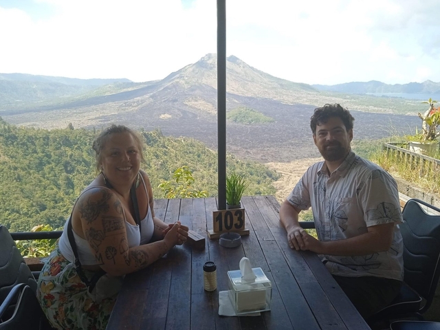 Two people sitting at a table with a scenic view of a volcano.