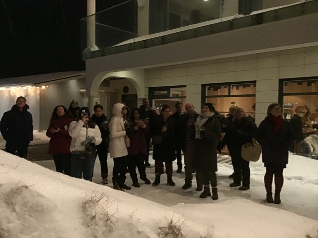 Group of people gathered outside in a snowy setting at night.