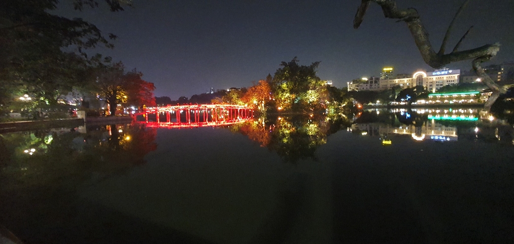 Lit bridge reflecting in a lake at night.