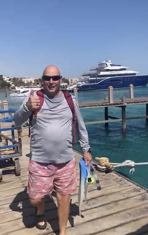 Person giving a thumbs up on a dock with boats.
