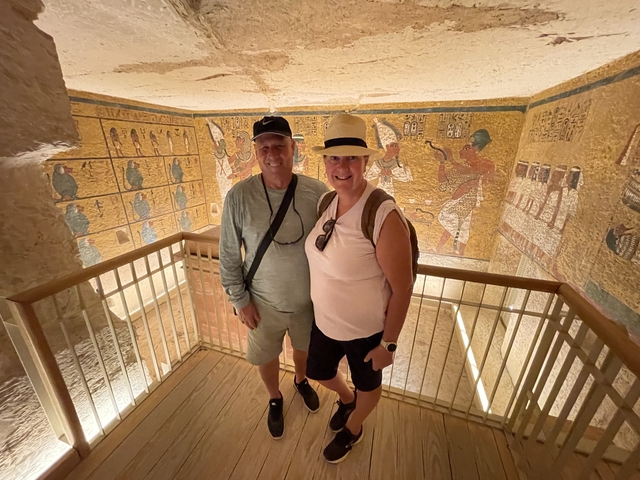 Couple standing inside an ancient structure decorated with murals.