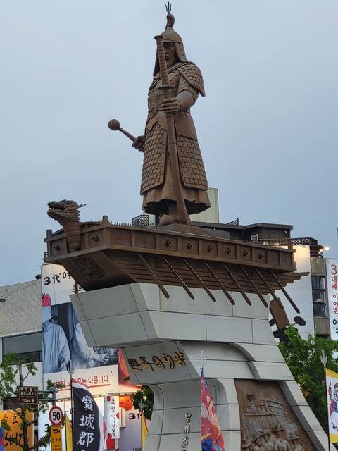 Statue of a historical figure next to some modern structures.