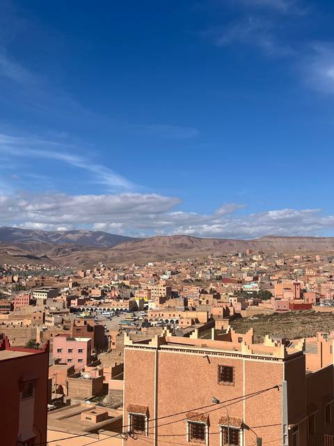 A panoramic view of a Moroccan city with traditional architecture and a mountainous backdrop.
