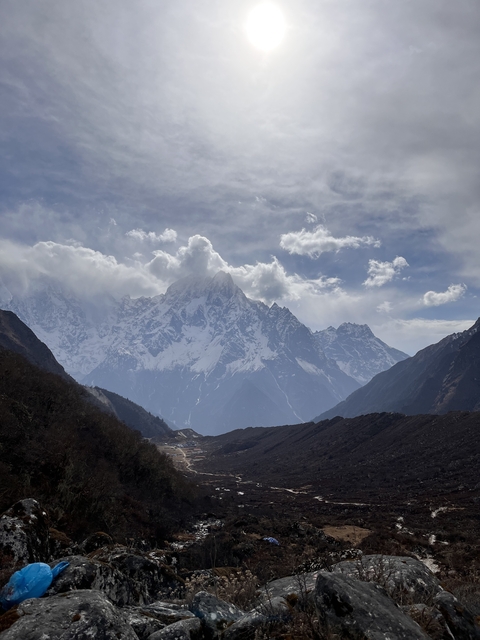 Snow-covered Himalayan mountains with clouds and sunlight.