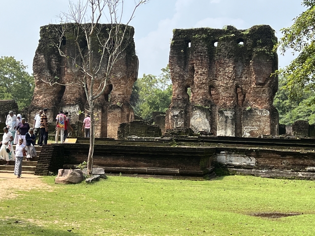 Group of people exploring ancient ruins with weathered brick structures.