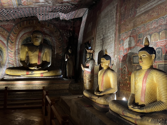 Statues of Buddha in various positions inside a dimly lit cave.