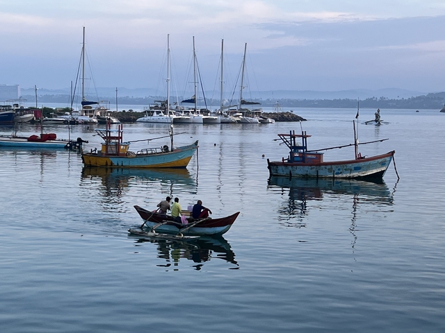Colorful fishing boats with people in calm water.