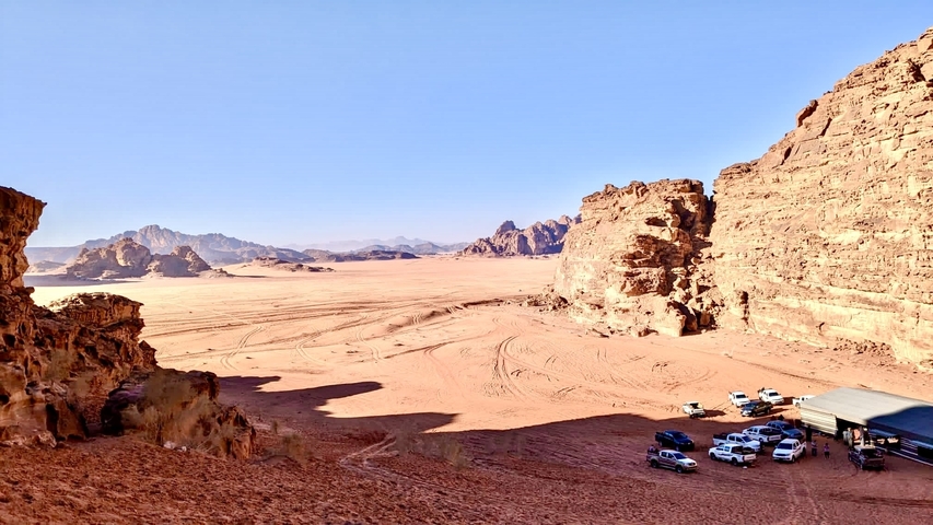Desert landscape with vehicles and rock formations.