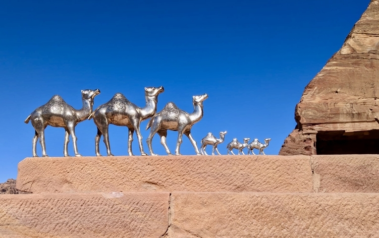 Camel sculptures on a stone platform in the desert.