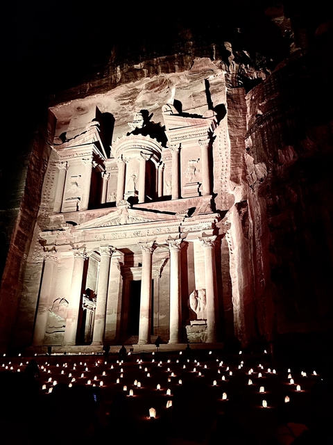 Illuminated facade of Petra's Treasury at night.