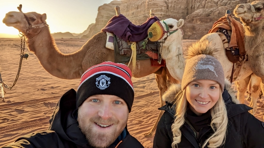Couple with camels in a desert setting.