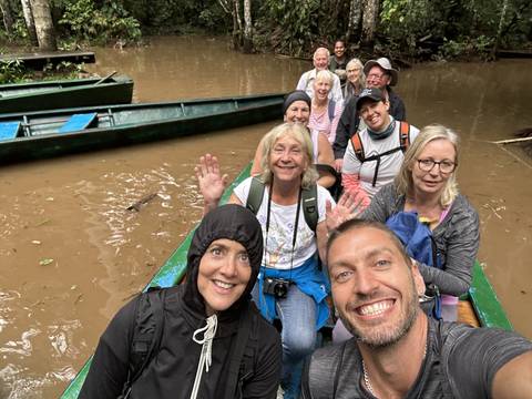 Group of people in a canoe on a muddy river.