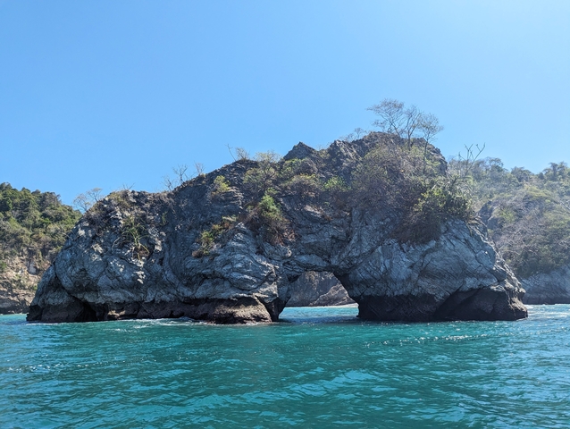 Rock formation resembling an arch over the ocean.