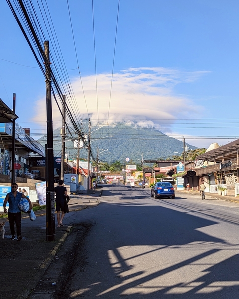 Street view with a mountain covered by clouds in the distance.