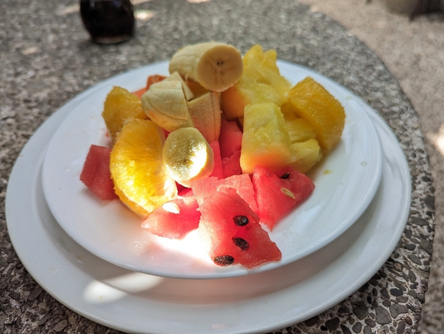 Plate of mixed tropical fruits in sunlight.
