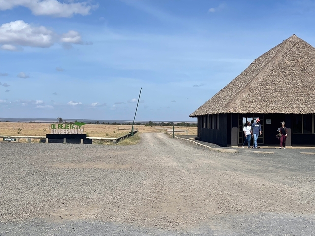 Entrance to Ol Pejeta Conservancy with people and sign.