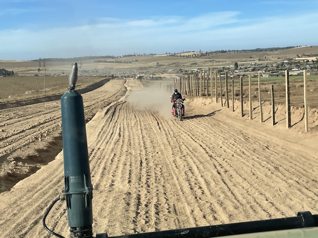 Motorcyclist riding through a dusty path.