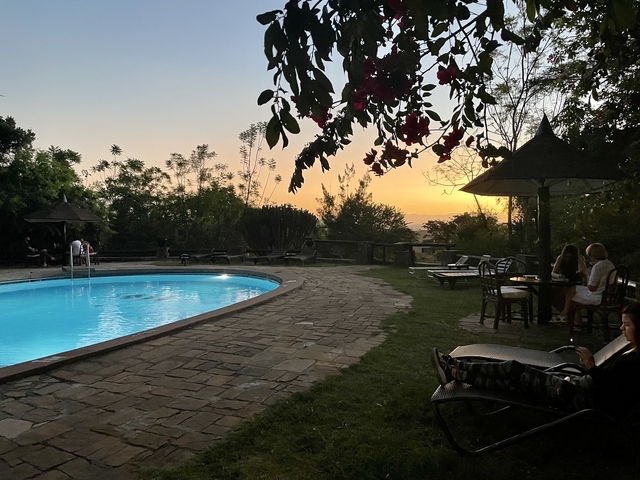People relaxing by a poolside at sunset.