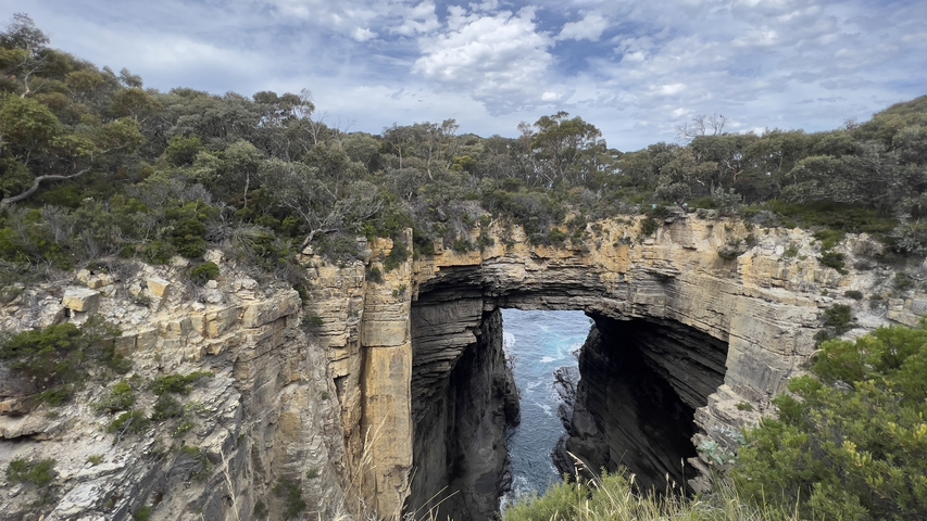 Natural arch in a rocky cliff by the ocean.