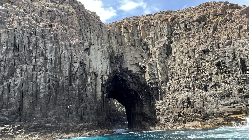 Cave entrance in high rocky cliffs.