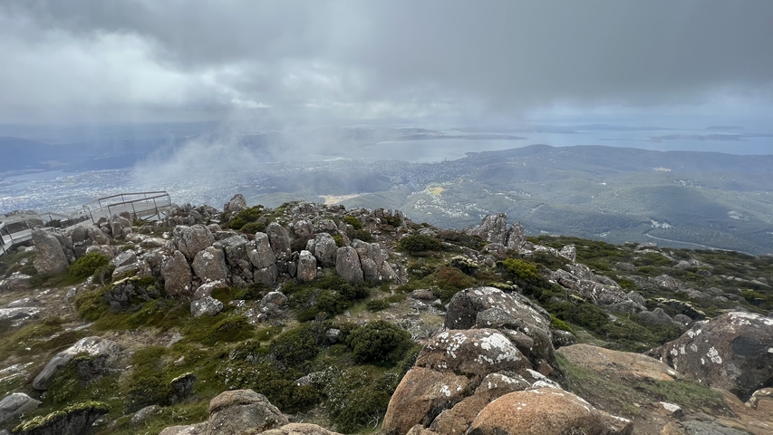 View from a mountain with fog and rocky terrain.