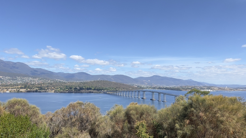 Bridge over a body of water with mountains in the background.