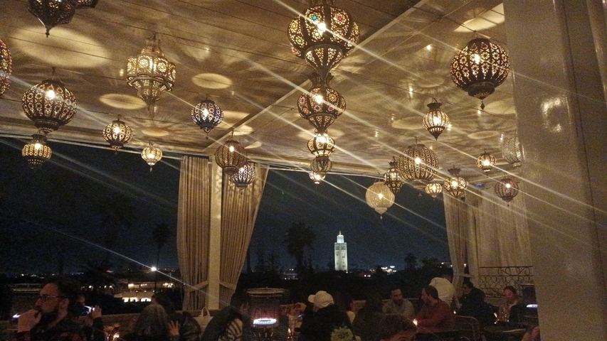 Covered rooftop with decorative lamps and cityscape at night.