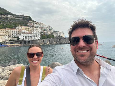Upside-down portrait of two people with a coastal background.