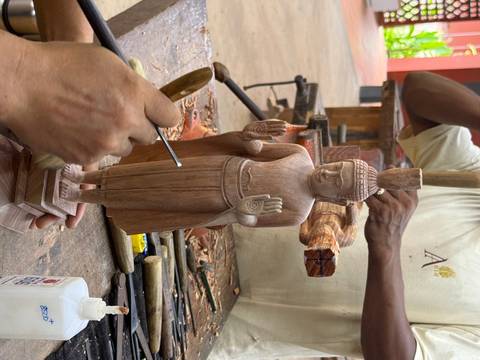 Wood carving of a statue in progress on a workbench.