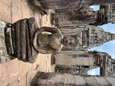 Ancient statue of Buddha surrounded by temple ruins.