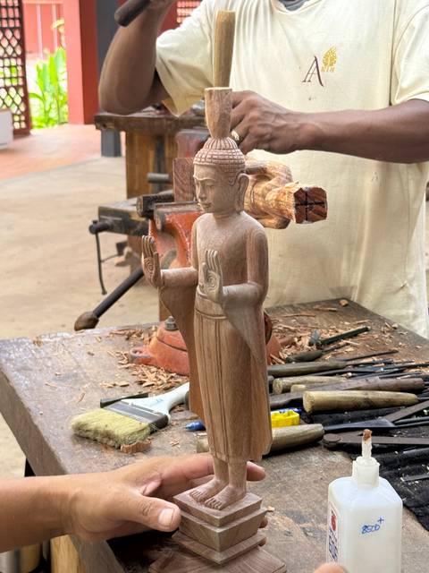 Wood carving of a statue in progress on a workbench.