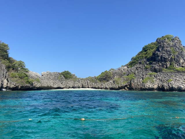 Clear blue waters with rocky island formations.