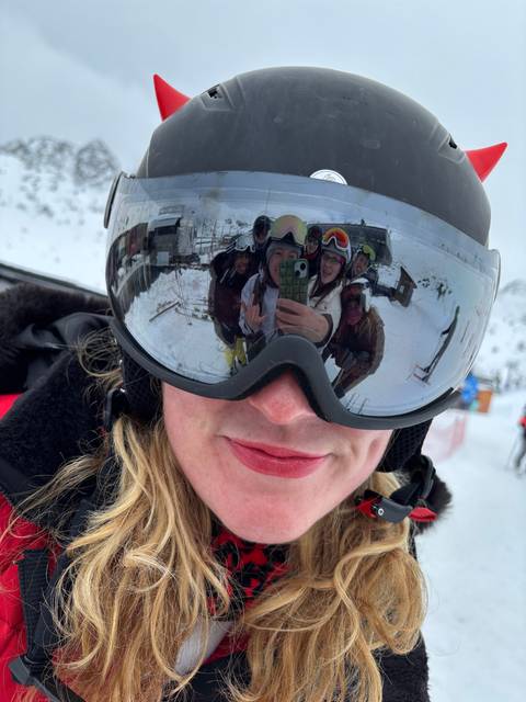 A close-up of a person wearing a helmet with a reflection of a group in the visor.