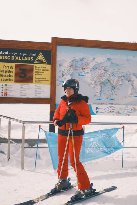 Person in ski gear holding poles with a map in the background.