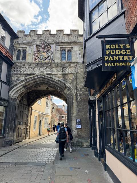 A historic street with archway and people walking.