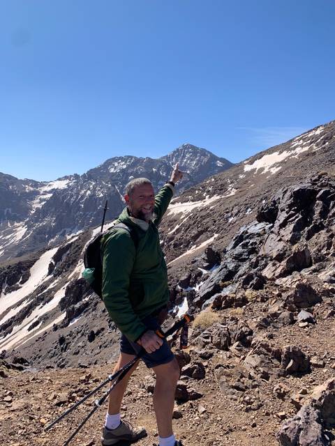Man pointing at a mountain peak during a hike.