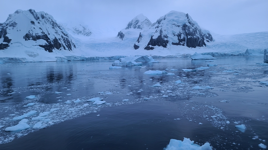 Iceberg-filled bay surrounded by snowy mountains.