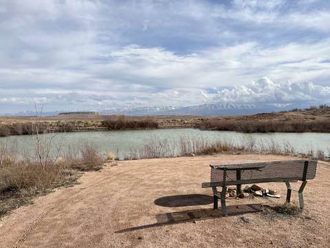 Bench by a river with distant mountains